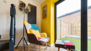 A room with a modern chair, a floor lamp, and a view of a backyard. - Chic Urban Haven with Double Bed House (Bristol City)