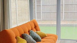 A modern orange sofa with textured cushions, a wooden coffee table, and a herringbone wood floor. - Chic Urban Haven with Double Bed House (Bristol City)