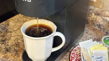 Une machine à café de la marque KEURIG verse du café dans une tasse blanche.