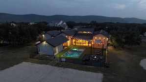 A residential property with a swimming pool, multiple houses, and a view of distant hills. - 5 Bed Room House with Pool, Pickleball, Basketball, Sand Volleyball on Hole #1  (Concan)
