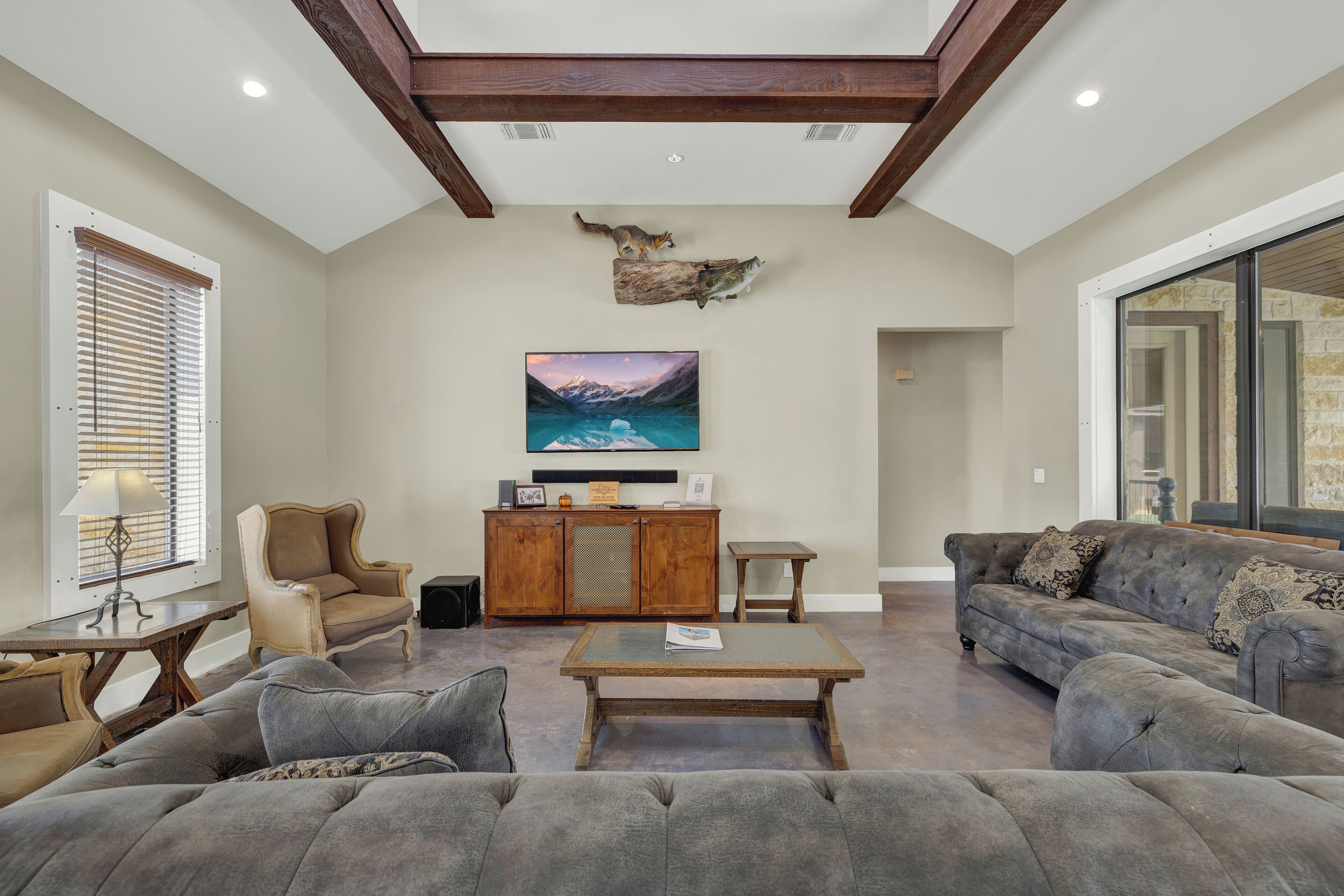 Un salon spacieux avec un haut plafond, un grand canapé, une table basse et une cheminée.