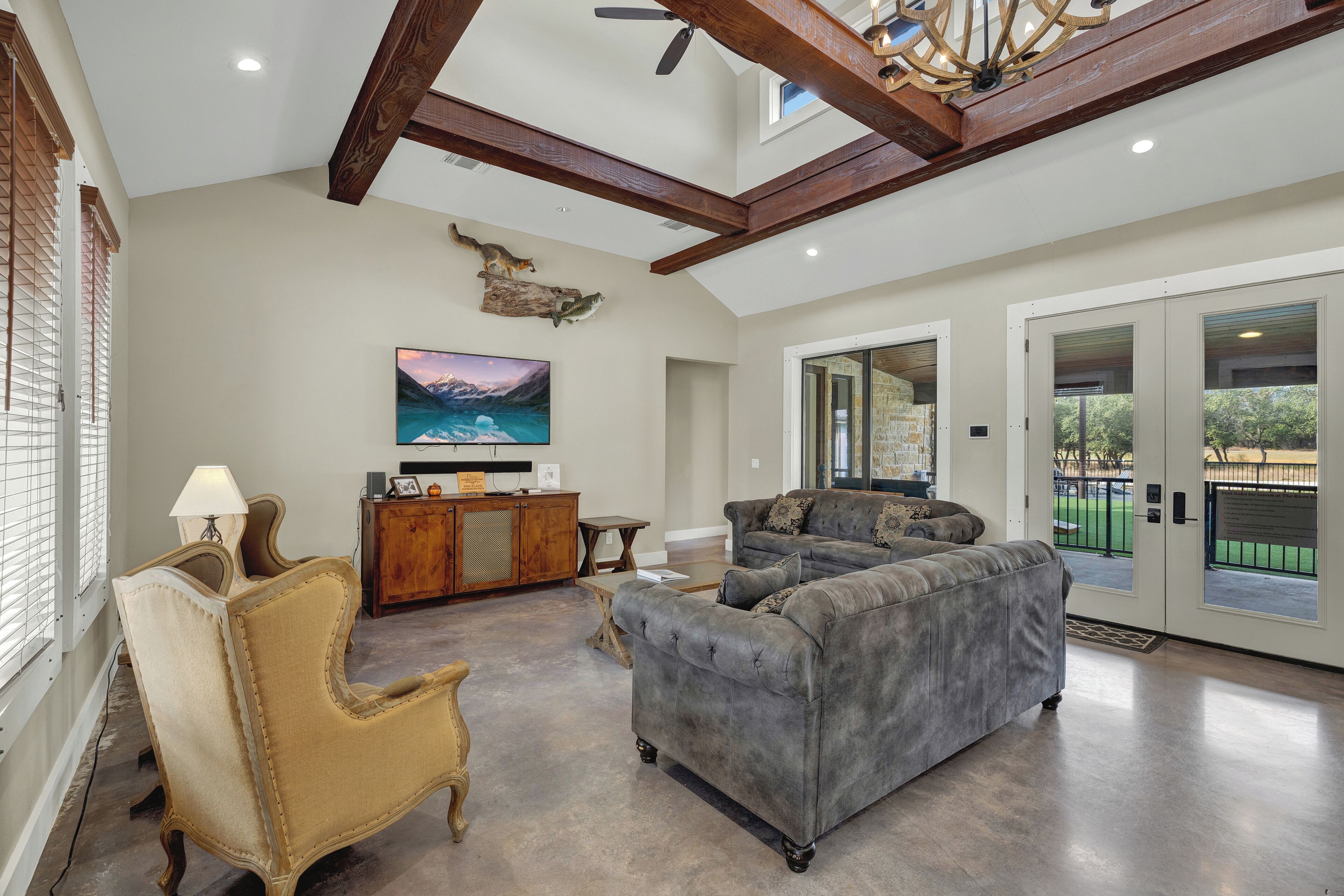 A spacious living room with a grey sofa, a wooden cabinet, and a mounted TV.