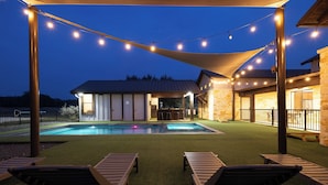 An outdoor pool area with lounge chairs and string lights. - 5 Bed Room House with Pool, Pickleball, Basketball, Sand Volleyball on Hole #1  (Concan)