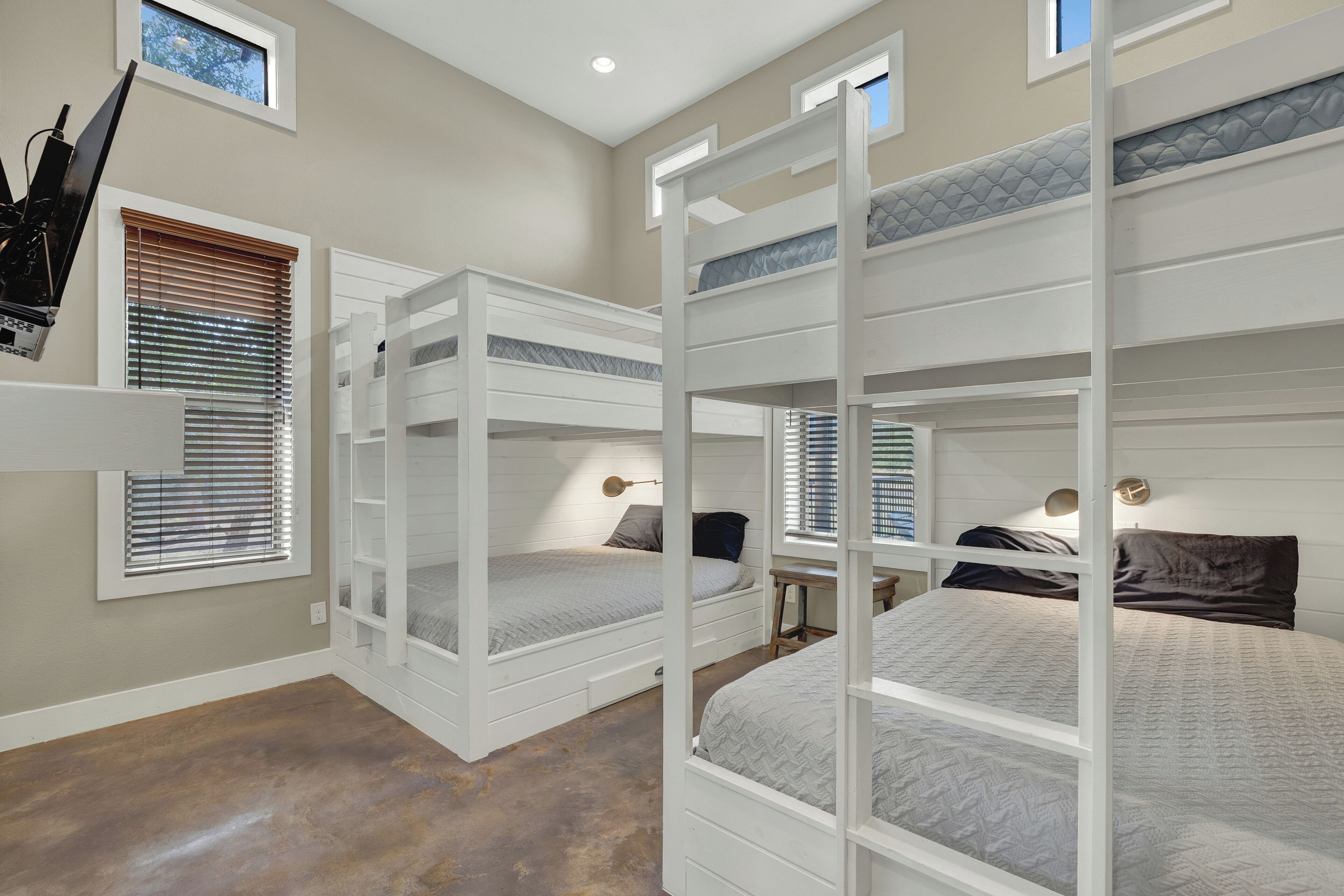 A room with bunk beds, built-in shelves, and a desk with a lamp.
