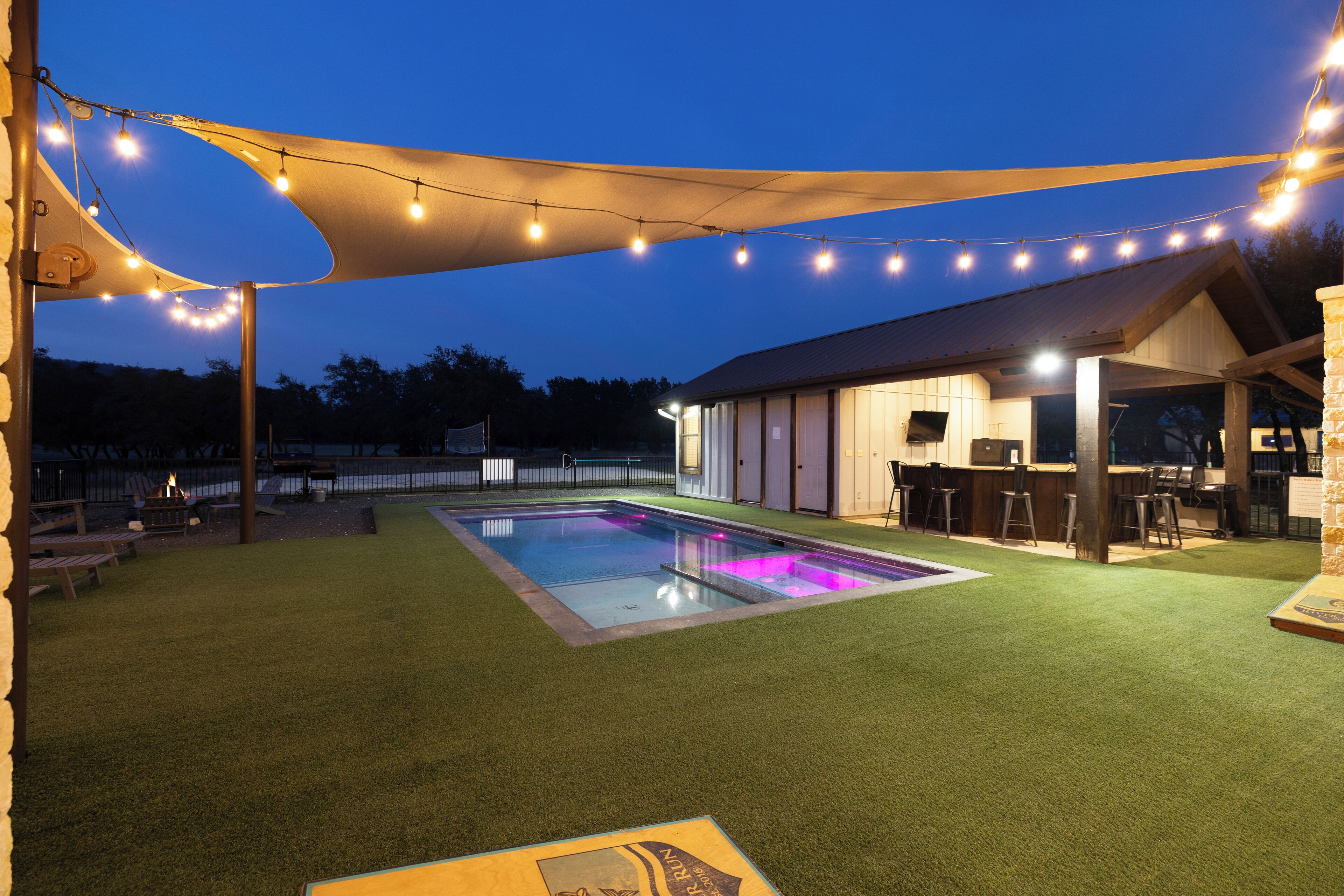 A backyard with a pool, outdoor seating, and string lights.