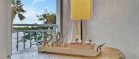 A round wooden table with a tray holding a lamp, bottles, and a 'Relax' sign.