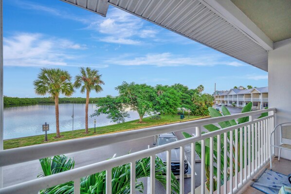 A balcony with a view of a lake, palm trees, and a parking area. - Little Harbor (Ruskin)