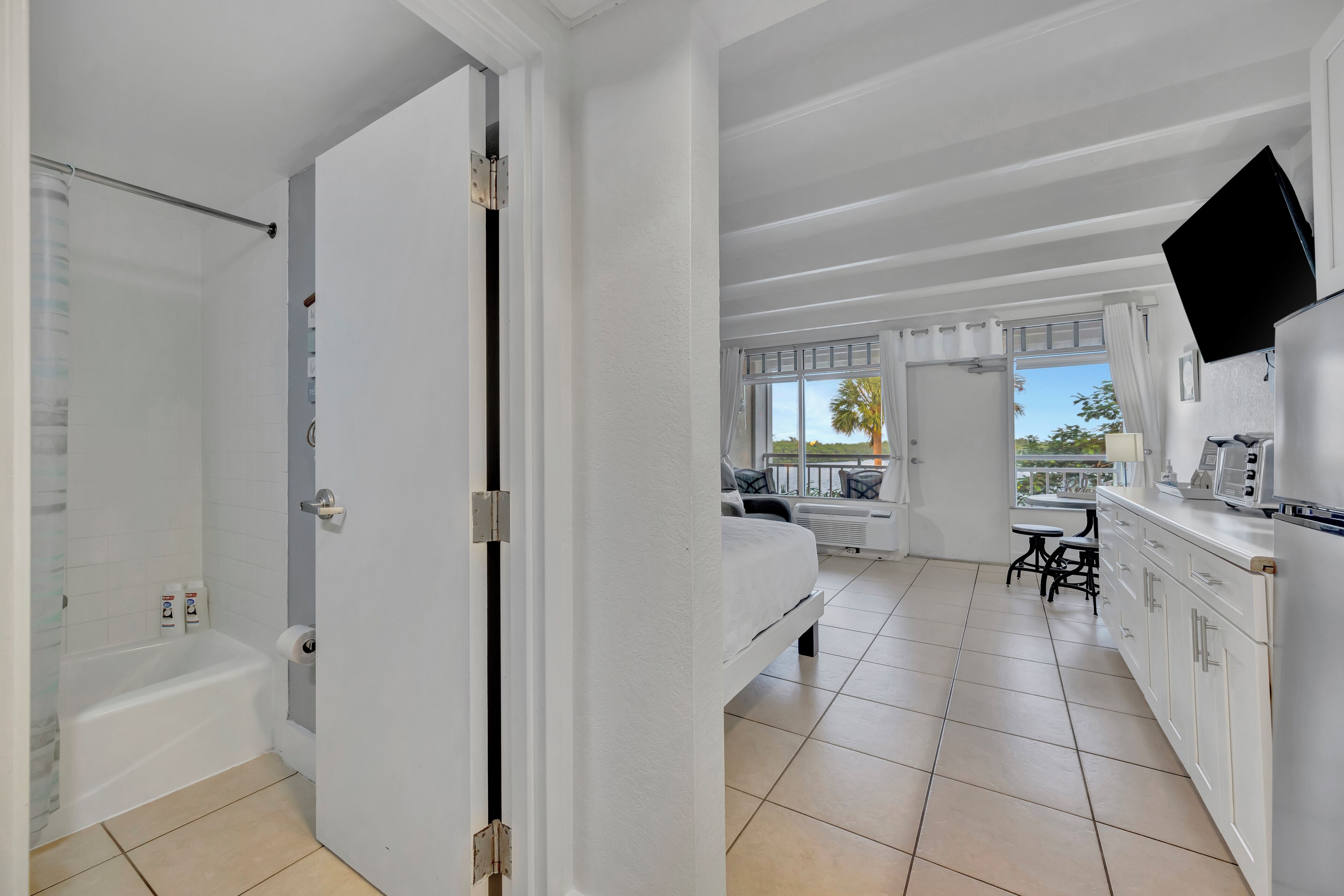 Una cocina moderna con armarios blancos, un televisor de pantalla plana y un comedor con mesa y sillas.