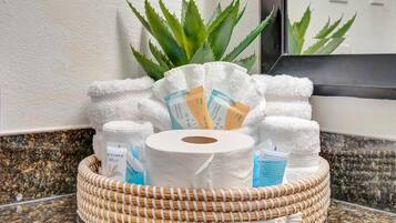 A bathroom vanity with a woven basket containing toiletries, a mirror, and an aloe vera plant.