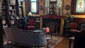 A traditional library with bookshelves, a fireplace, and a vintage sofa. - The Stegmaier Guest House (Wilkes-Barre)
