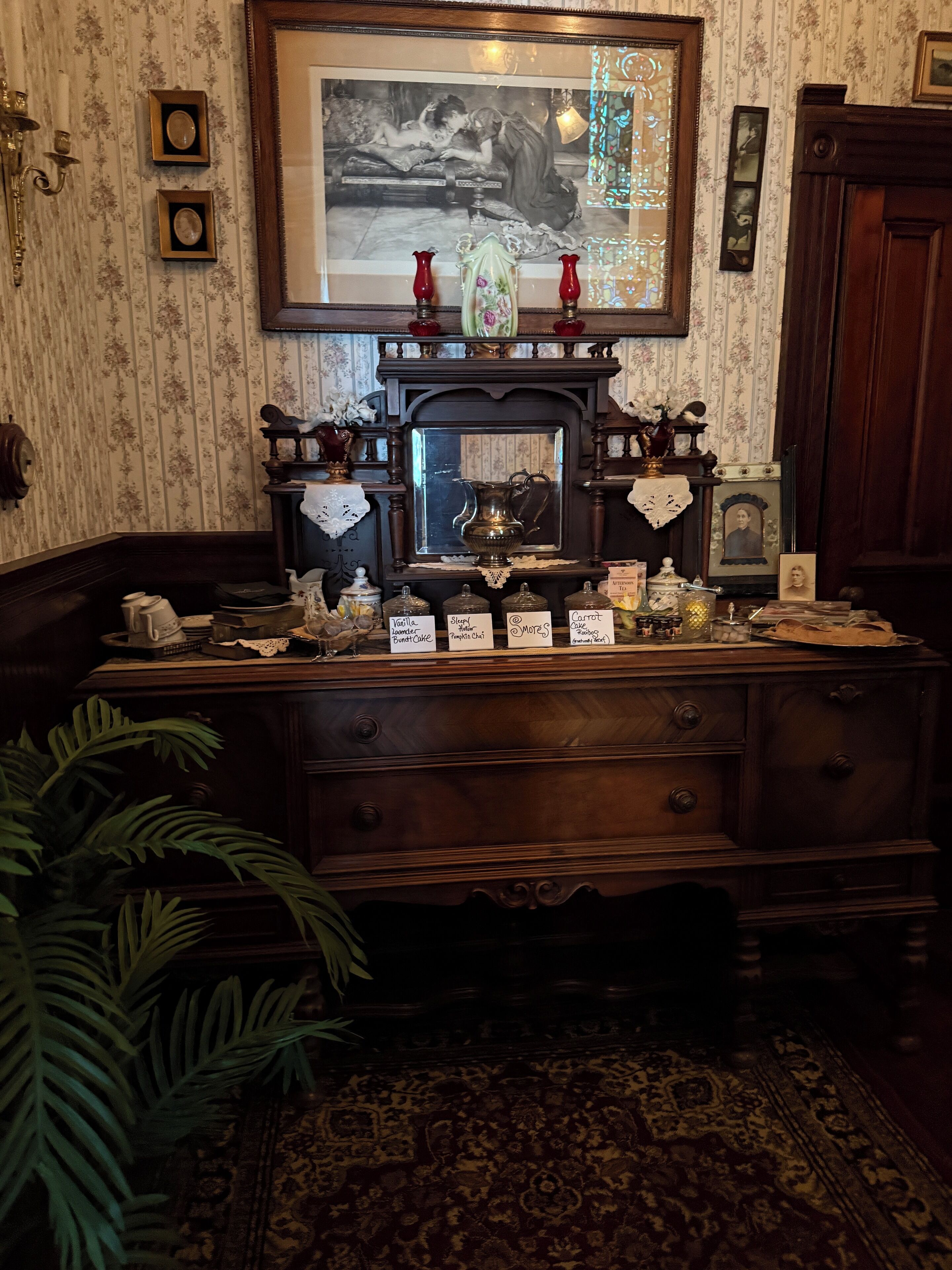 Habitación de estilo antiguo con un escritorio de madera, un cuadro enmarcado encima y una alfombra estampada.