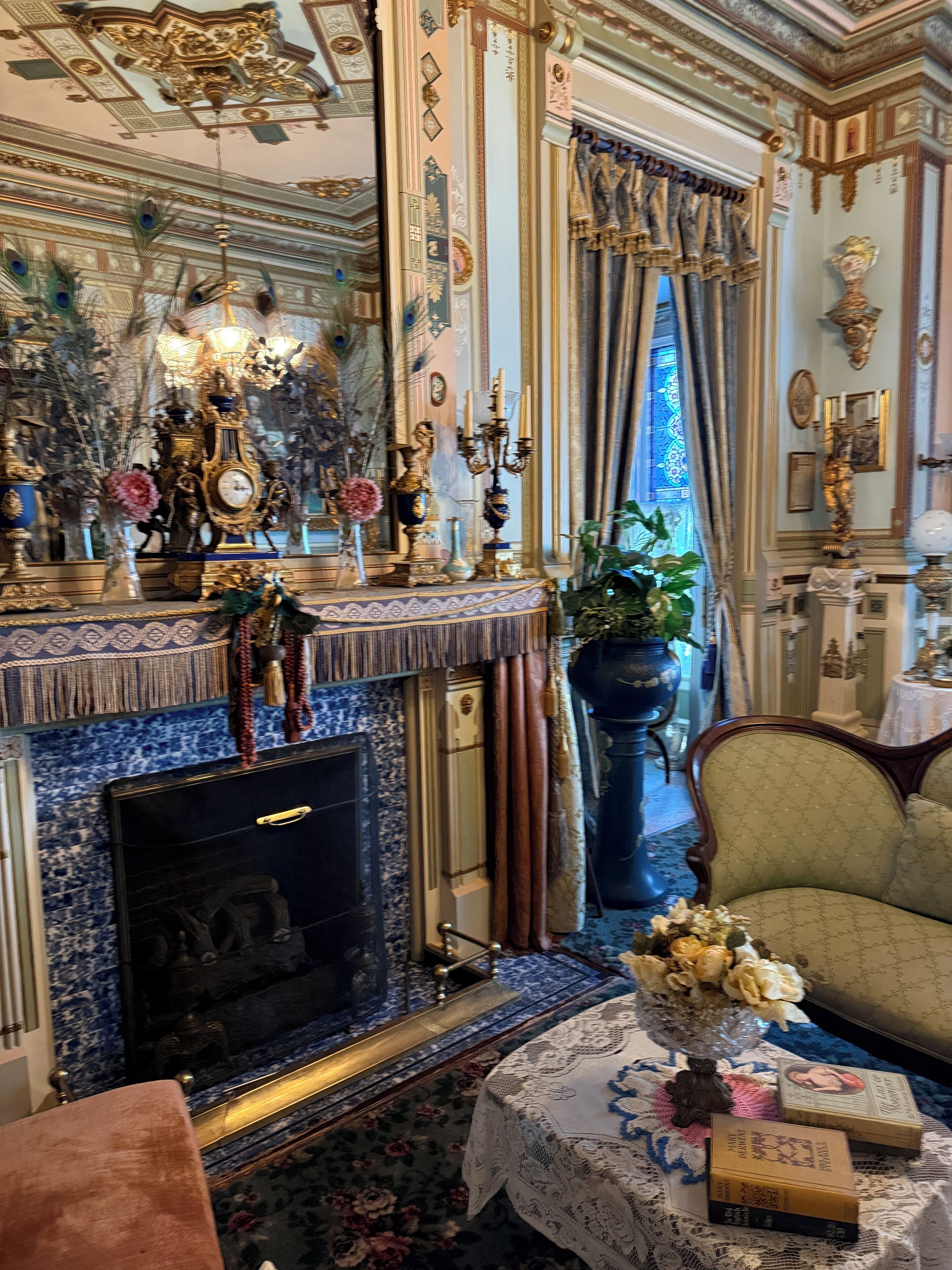 A richly decorated room with a fireplace, ornate furniture, and a large mirror.
