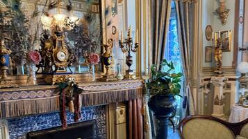 A richly decorated room with a fireplace, ornate furniture, and a large mirror.