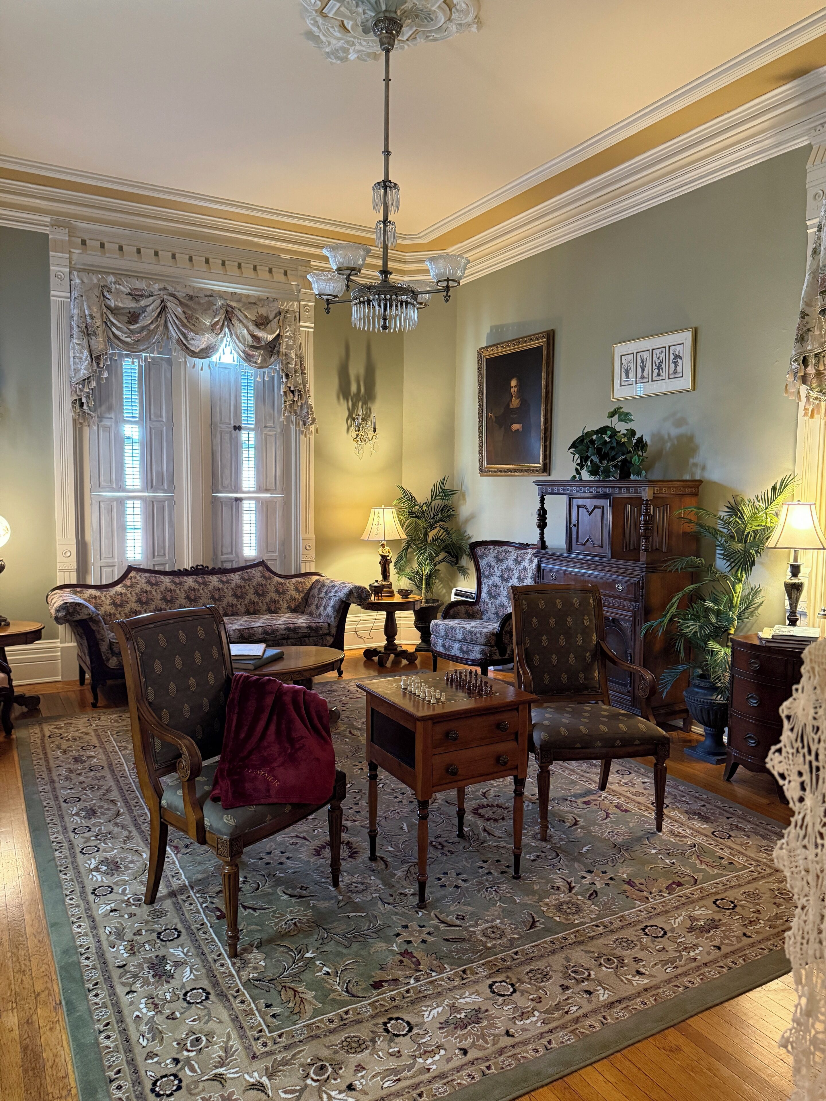 A traditional living room with a chandelier, patterned rug, and classic furniture.