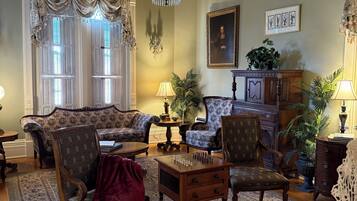 A traditional living room with a chandelier, patterned rug, and classic furniture.