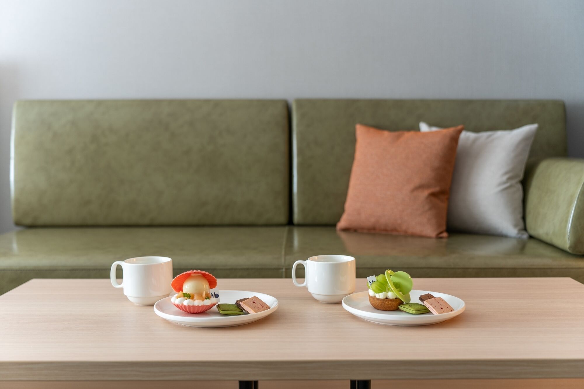 A dining table with two plates of food and two white cups.