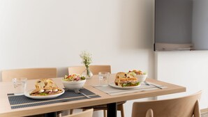 A dining table with two plates of food, a bowl of salad, and two glasses of water. - Regale Namba (Osaka)
