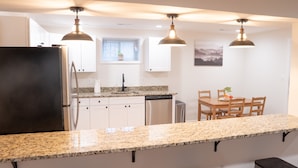 A modern kitchen with granite countertops, stainless steel appliances, and pendant lighting.