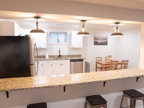 Una cocina moderna con encimeras de granito, electrodomésticos de acero inoxidable e iluminación colgante.