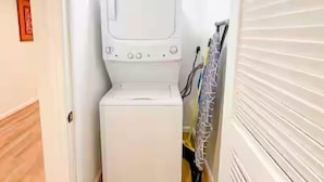 A laundry room with a washing machine and dryer, a door with a handle, and a wall-mounted towel rack.