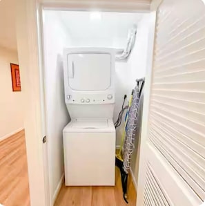 Un cuarto de lavandería con lavadora y secadora, una puerta con picaporte y un perchero de toallas en la pared.