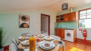 A dining area with a table set for breakfast, a washing machine, and a fire extinguisher in the background. - Bright & Spacious Flat in Porto by HostWise (Porto)