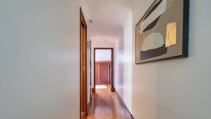A hallway with wooden flooring and a framed abstract painting on the wall. - Bright & Spacious Flat in Porto by HostWise (Porto)