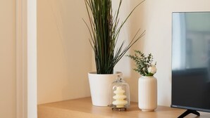A wooden shelf with a potted plant, a glass candle holder, and a vase with flowers. - Modern & Stylish Flat by HostWise (Porto)