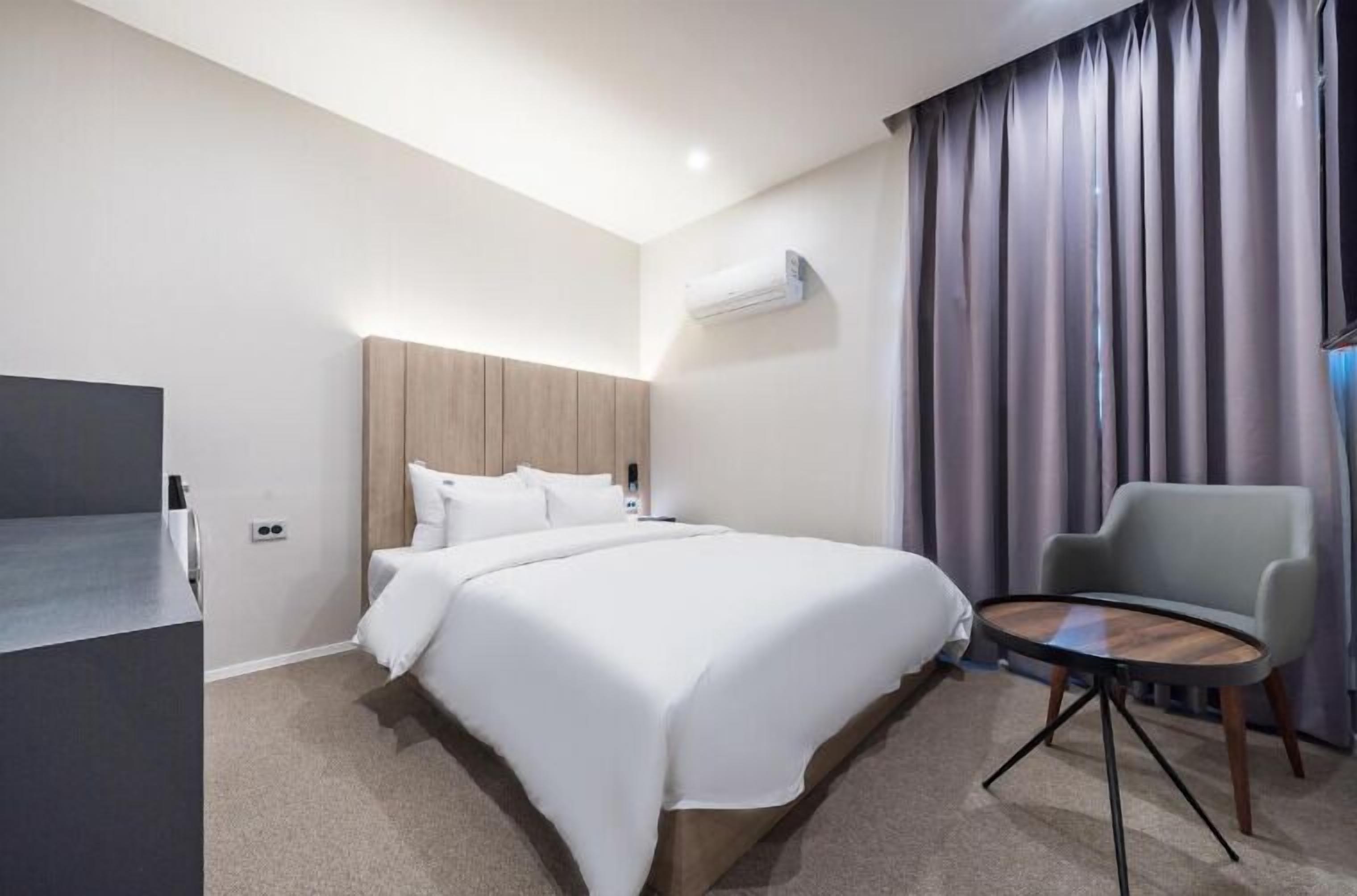 Une chambre d’hôtel équipée d’un lit, d’un bureau, d’une chaise et d’un appareil de climatisation.