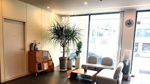 A modern hotel lobby with a reception desk, seating area, and large windows offering a view of the street. - POHANG HOTEL LA TERRACE (Pohang)