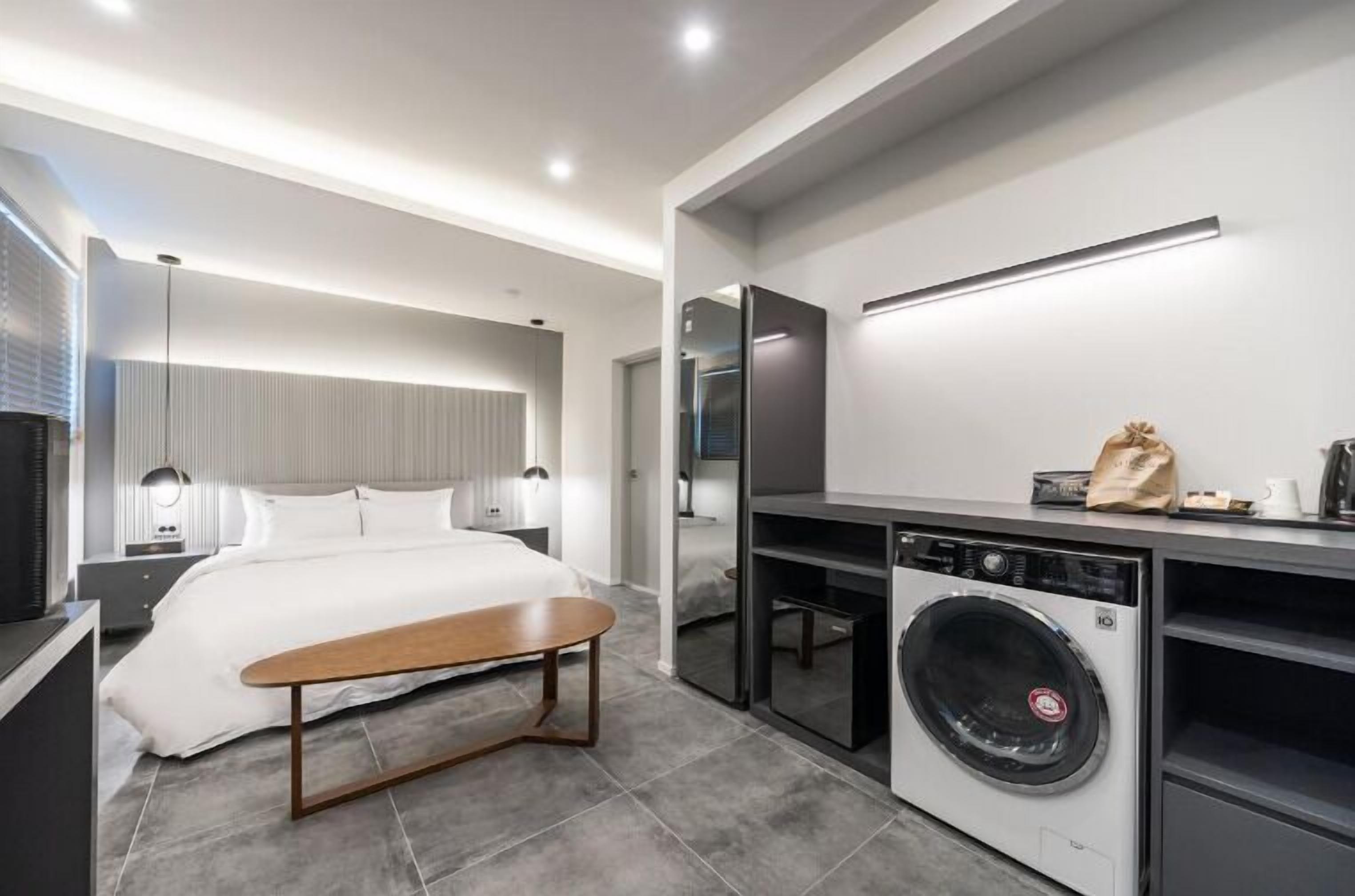 Una camera d'albergo moderna con un letto, un comodino e una lavatrice.