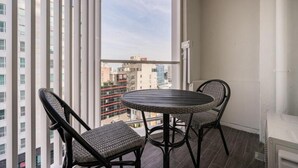 A balcony with a round table and two wicker chairs, overlooking a cityscape with high-rise buildings. - POHANG HOTEL LA TERRACE (Pohang)