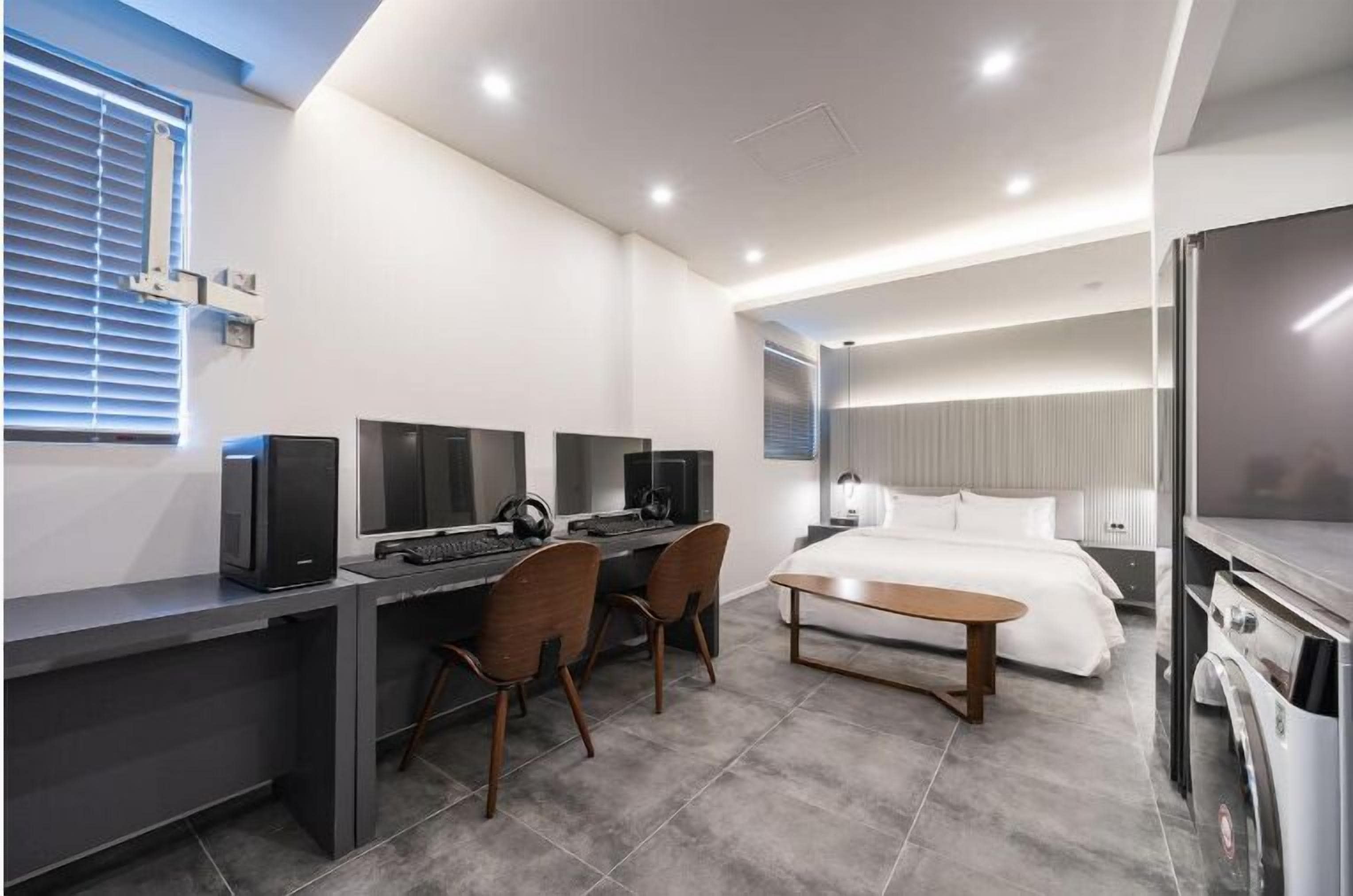 Ein modernes Hotelzimmer mit Schreibtisch, zwei Stühlen, einem Bett und einem Fernseher.