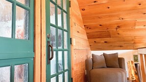 A wooden interior with a green door, a sofa, and a wooden ceiling. - Tranquility Heights: Deck, 3.5 acres, Darts, Movie Room, Desk w/Printer (Ozark)
