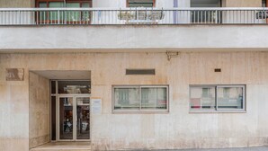 Un immeuble avec une entrée au rez-de-chaussée, un balcon doté d’une balustrade et deux fenêtres à l’étage supérieur.