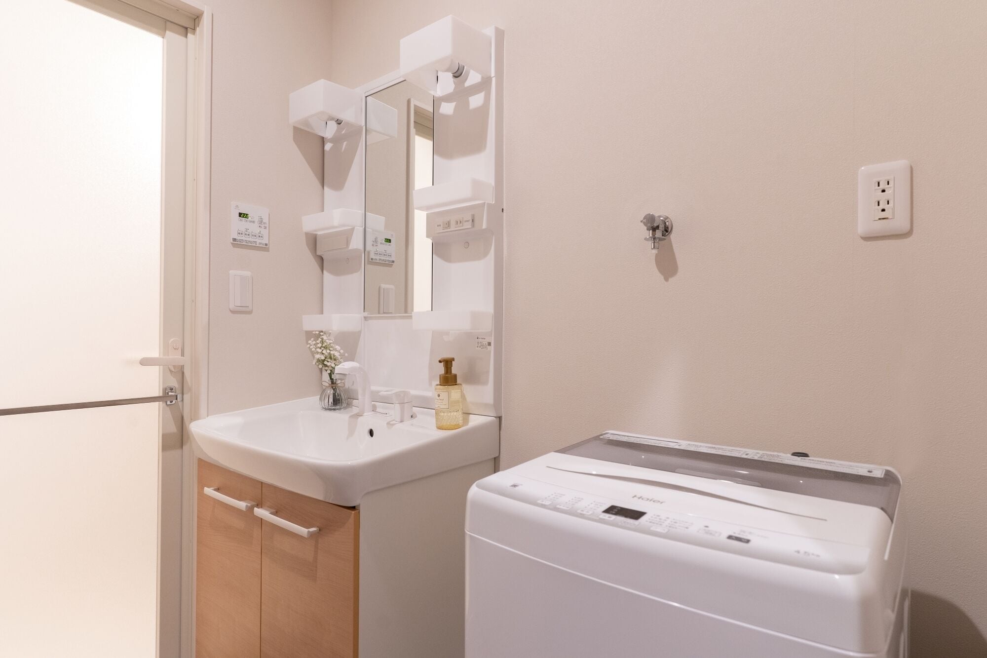 A bathroom with a sink, mirror, and a white washing machine.