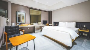 Una habitació d'hotel amb un llit, una taula de treball, una cadira, un mirall, una televisió i una taula de nit.
