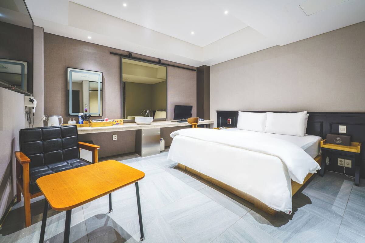 Une chambre d’hôtel équipée d’un lit, d’un bureau, d’une chaise, d’un miroir, d’une télévision et d’une table de chevet.