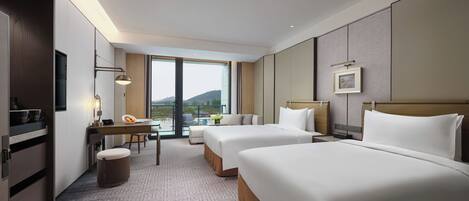 Quarto de hotel com duas camas, uma mesa, uma cadeira, televisão e varanda com vista para as colinas.