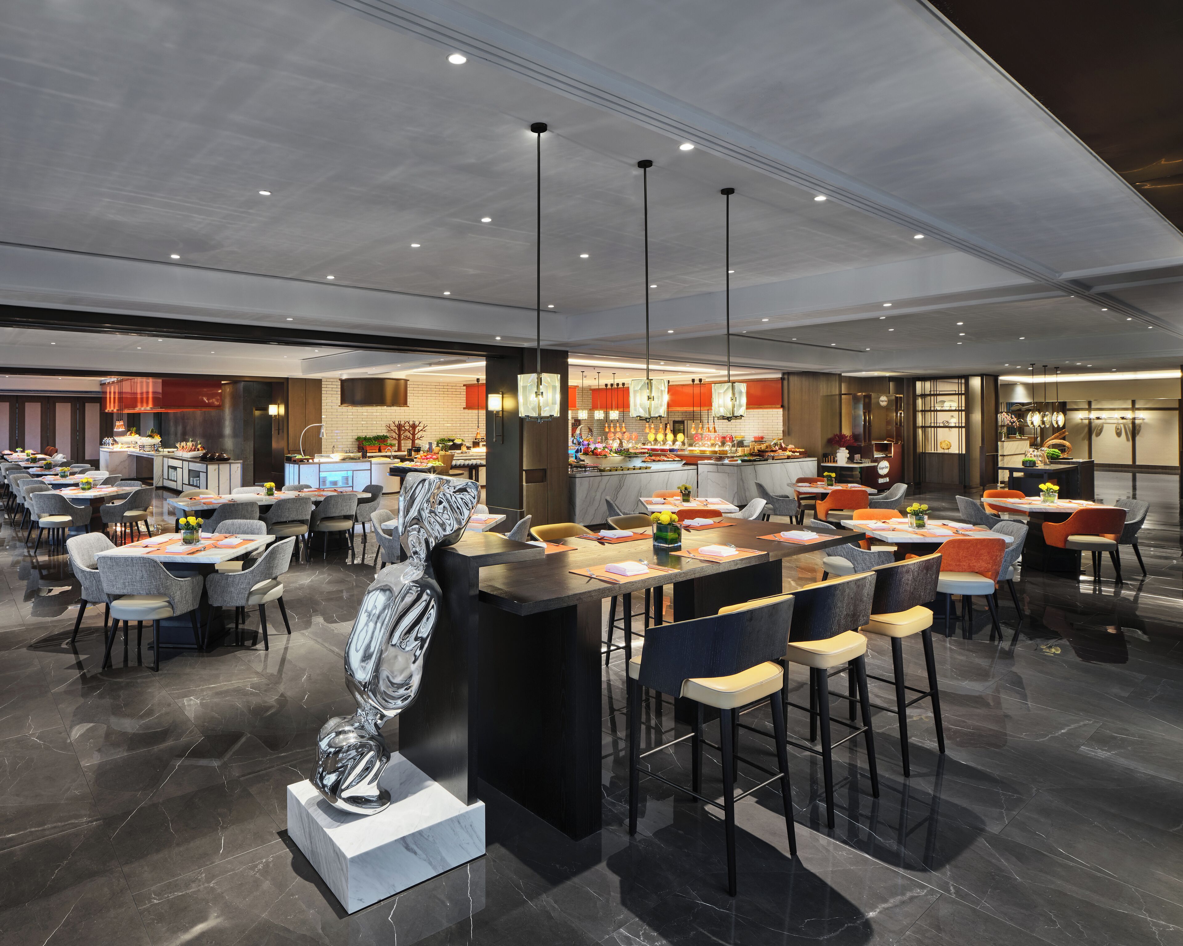 A modern restaurant with multiple dining areas, a central bar, and a kitchen visible in the background.