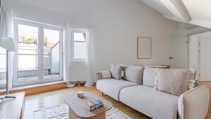 A modern living room with a light-colored sofa, a wooden coffee table with books, and large windows with white curtains. - Blueground | Landstraße, view, nr Belvedere (Vienna)