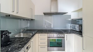 A modern kitchen with a gas stove, oven, microwave, and stainless steel sink. - Blueground | Landstraße, view, nr Belvedere (Vienna)