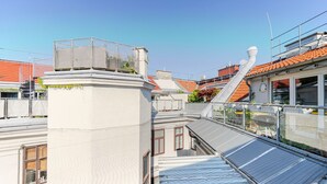 A rooftop terrace with a metal railing, a white building, and a red-tiled roof. - Blueground | Landstraße, view, nr Belvedere (Vienna)