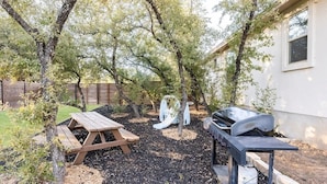 Ein Garten mit Picknicktisch, Grill und Rutsche.