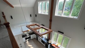 Amplio espacio tipo loft con techos altos, ventanas grandes y cocina equipada con electrodomésticos modernos.