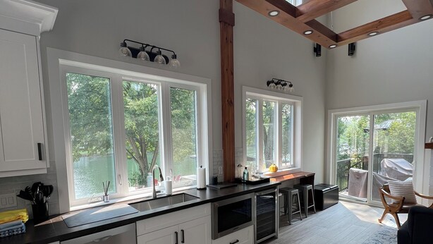 Una cocina amplia con ventanas grandes, un techo alto con vigas a la vista y un moderno lavamanos de acero inoxidable.