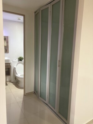 Ein Flur mit Toilette, Waschbecken und einem Schrank mit Pflanze.