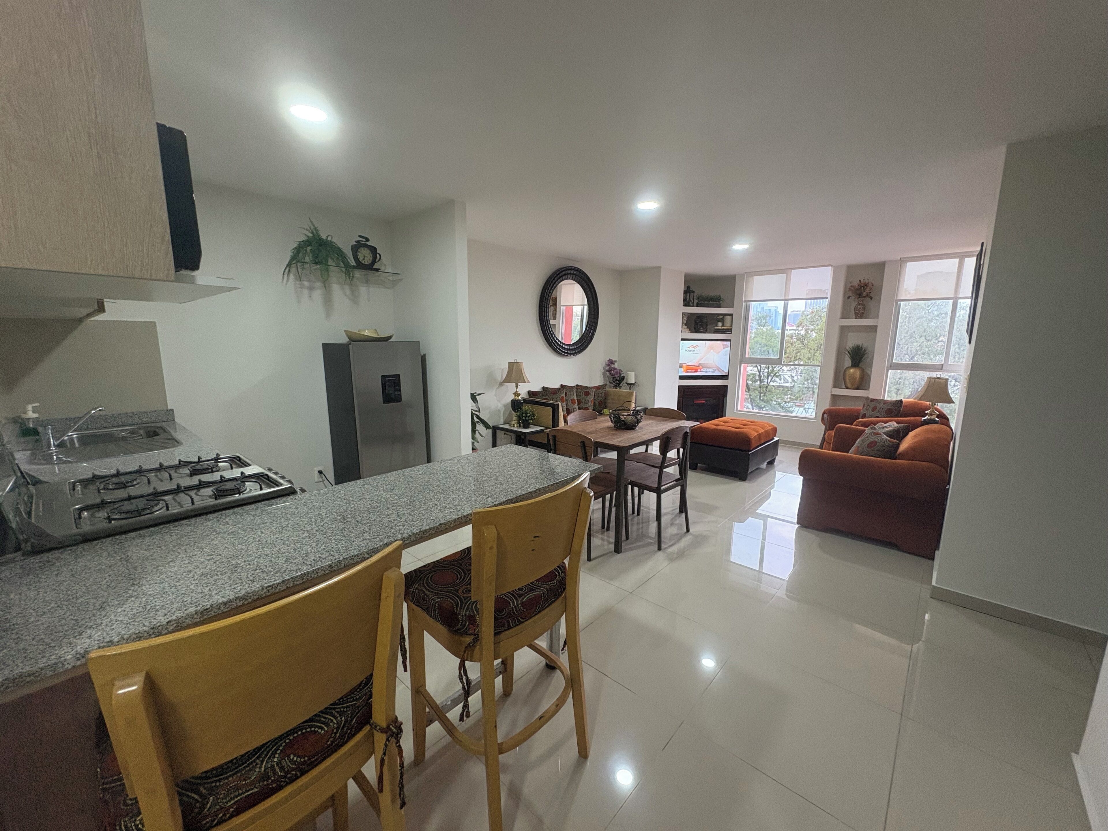 Una cocina moderna con estufa a gas, refrigerador y comedor con mesa y sillas.