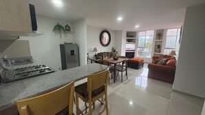 A modern kitchen with a gas stove, a refrigerator, and a dining area with a table and chairs. - Cozy apartment close to everything CDMX! (Ciudad de México)
