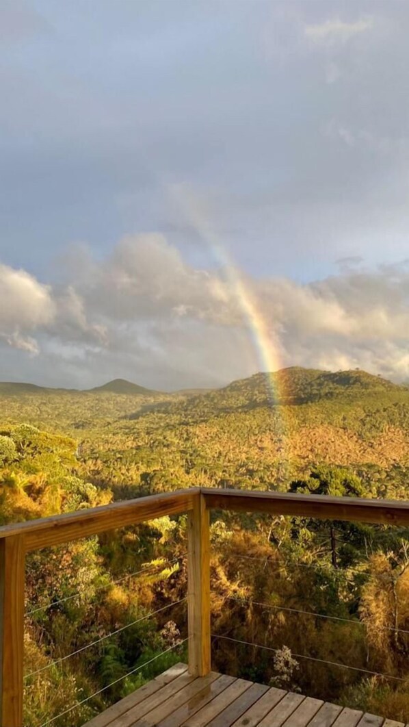 Um deck de madeira com vista para uma paisagem montanhosa e um arco-íris.